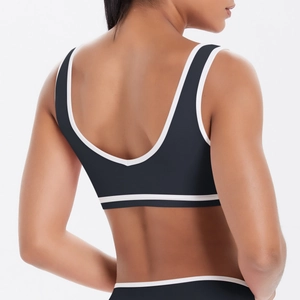 Détail du dos nu en U de la brassière de sport noire avec liserés blancs contrastants de yoga