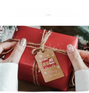 Detail of kraft paper Christmas gift tags with snowman and red bus illustration on a gift box