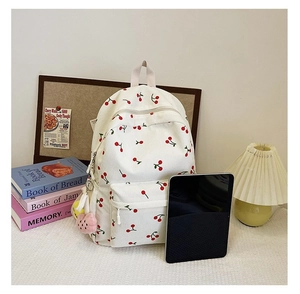 Detail of corduroy cherry backpack with plush charm in a cozy aesthetic workspace