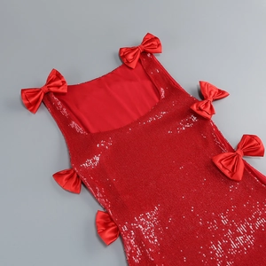 Detail of red sequined evening dress featuring satin bows and shimmering texture