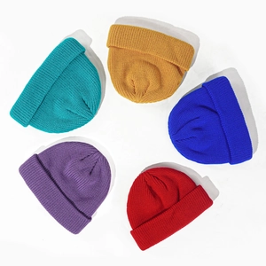 Close-up of five knitted beanies in teal, yellow, blue, red and purple on white background