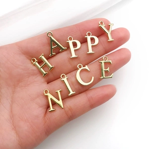 Nahaufnahme goldener Legierungsbuchstaben HAPPY NICE für DIY-Schmuckherstellung