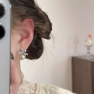Detail of elegant bow earrings with sparkling pavé crystals and round champagne pearl