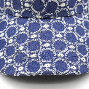 Dettaglio macro del ricamo floreale bianco su cappello da baseball in denim blu scuro