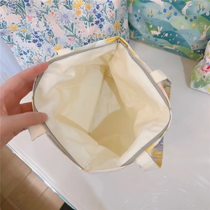 Gros plan sur l'intérieur spacieux et la fermeture éclair du petit sac en toile fleurie
