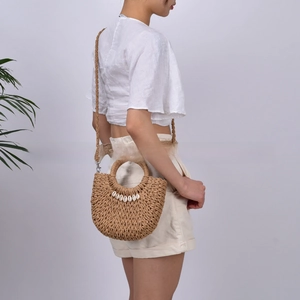 Detail of handmade woven straw bag with sea shell accents and circular handles