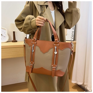 Detailed view of the contrast color leather tote bag with buckles and zipper pockets