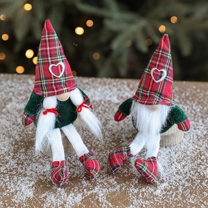 Pair of festive Christmas gnomes in red plaid and green velvet on a snowy wood surface