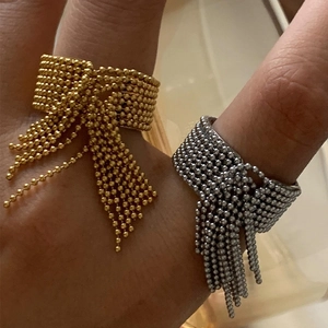 Detail of beaded tassel rings in gold and silver finish with cascading metal chains
