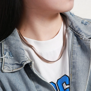 Close-up of rose gold flat snake bone chain necklace worn on neck with metallic texture