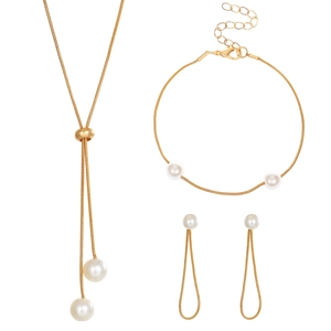 Detail of gold jewelry set with white pearls featuring tassel necklace and open bangle