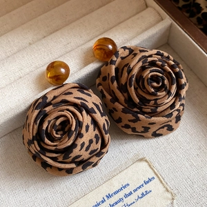 Detailed macro view of leopard print fabric rose earrings with an amber round bead accent