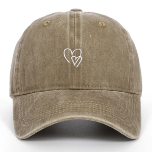 Dettaglio del ricamo a doppio cuore bianco sul cappellino in cotone lavato vintage