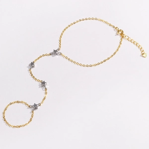Detail of 18k gold finger bracelet featuring five silver star charms and heart charm