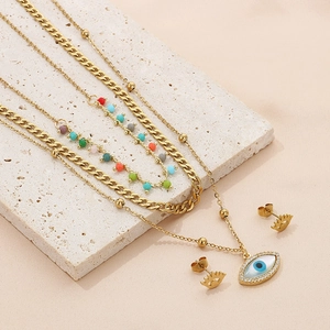 Detailed set of gold layered necklaces and evil eye earrings on a stone pedestal