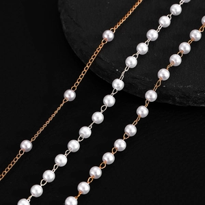 Détail d'un collier multicouche doré avec perles blanches sur fond d'ardoise noire