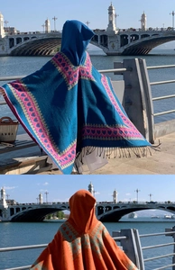 Détail d'un poncho bohème à capuche avec motifs jacquard géométriques et longues franges noires