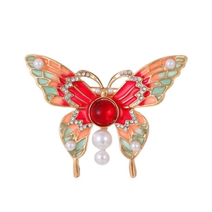 Detailed macro of a vintage butterfly brooch with red crystal, pearls, and colorful enamel