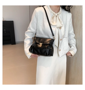 Detail shot of black pleated leather crossbody bag featuring vintage gold lock on model