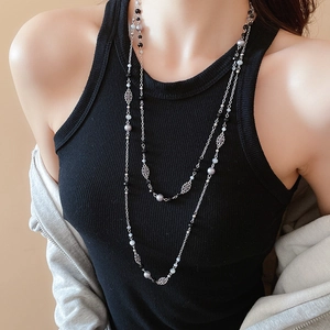 Detail of layered pearl necklace with floral silver beads on a black ribbed top