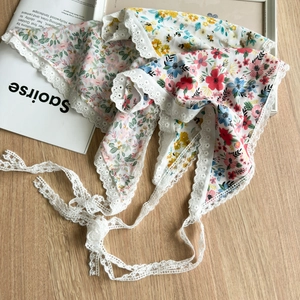 Detail of floral lace-trimmed bandanas in pastel colors on a rustic wooden table