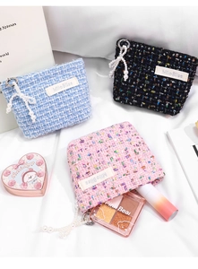 Detailed view of tweed makeup bags with pearl pendants in pink, blue, and black colors