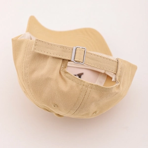 Detail of light khaki baseball cap showing adjustable fabric strap and silver metal buckle
