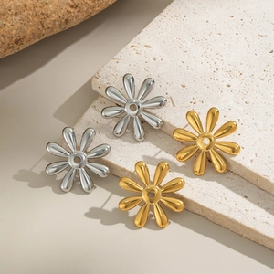 Elegant 18k gold and silver floral stud earrings displayed on natural stone