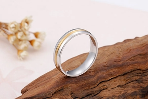 Détail d'une bague bicolore en acier inoxydable avec bande dorée sur bois