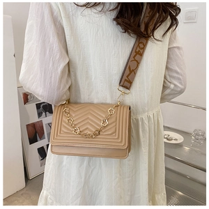 Detail of beige quilted flap bag with golden flower chain and jacquard woven strap