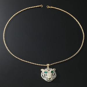 Macro shot of gold lion head pendant with green crystal eyes and clear rhinestone detail