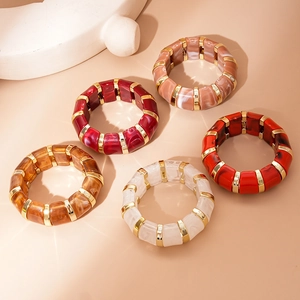 Detail showing colorful acrylic geometric bangles with gold spacers and resin texture