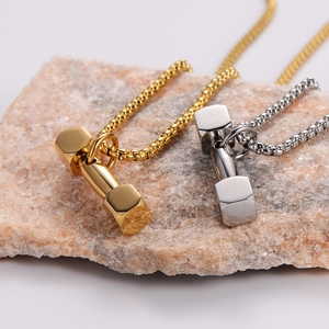 Polished stainless steel dumbbell pendant necklaces in gold and silver on a textured stone