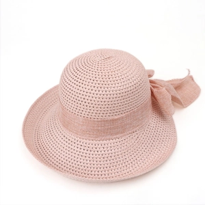 Detailed view of pink straw hat featuring a large elegant ribbon bow on a white background