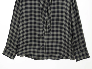 Detail shot of black and green plaid fabric with buttons on long sleeve shirt