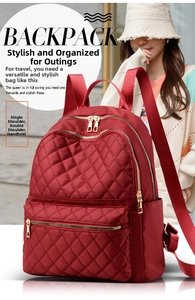 Detail of burgundy quilted backpack featuring multiple zipper pockets and gold hardware