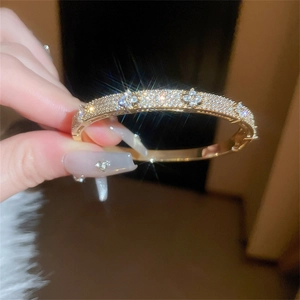 Macro detail of gold four-leaf clover bracelet encrusted with sparkling zircon stones
