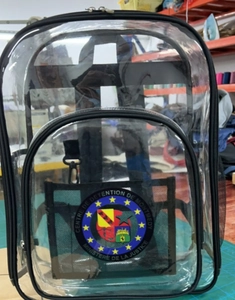Detailed macro view of a clear PVC backpack featuring a French judicial emblem and black trim