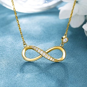 Elegant gold infinity necklace with zircons on a textured blue background