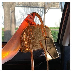 Detail of golden shell bag with crocodile texture and metal strap in sunset light