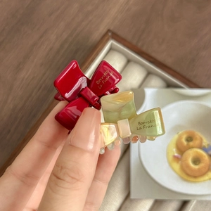 French style acetate bow hair claws in deep red and marble green shown in hand