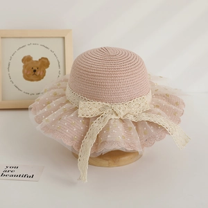 Détail d'un chapeau de paille rose pour filles avec ruban en dentelle et nœud en tulle