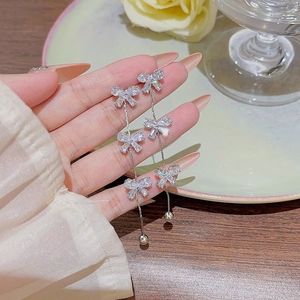 Close-up of elegant silver bow tassel earrings with sparkling rhinestones held by hand