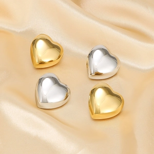 Detail view of heart-shaped 18K gold and silver steel earrings on silk fabric