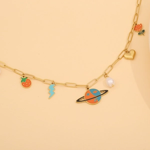 Detail of gold paperclip chain necklace with strawberry, heart and pearl charms