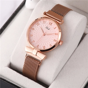 Détail d'une montre en maille or rose avec cadran rose à texture géométrique sur coussin