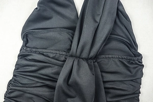 Close-up of black bodycon dress featuring elegant ruched fabric and a center twist knot detail