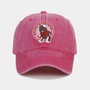 Detailed close-up of pink washed cotton baseball cap with embroidered teddy bear patch