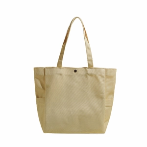 Minimalist beige canvas tote bag featuring dual side pockets and a secure metal snap button