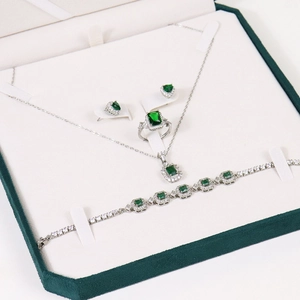 Silver jewelry set with green gemstones in a premium velvet octagonal display box